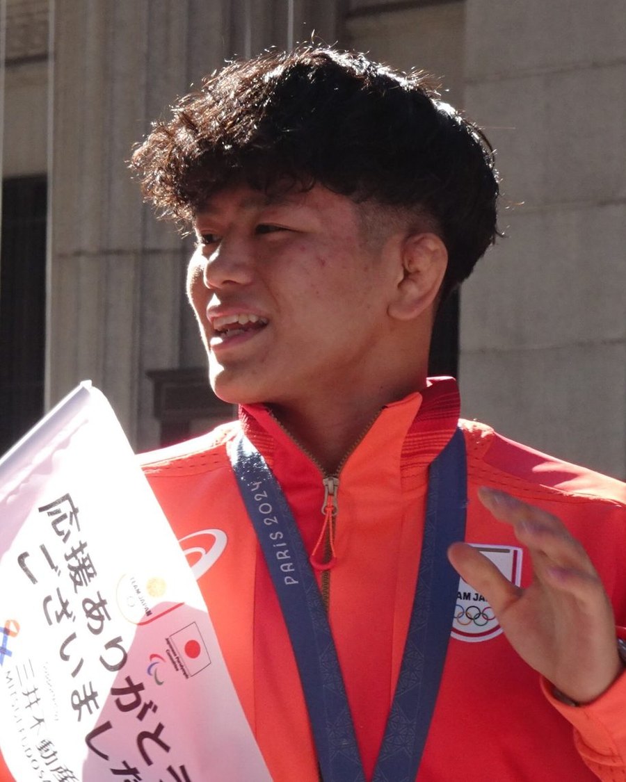 Kotaro Kiyooka in his Team Japan jacket, smiling at a crowd in Tokyo